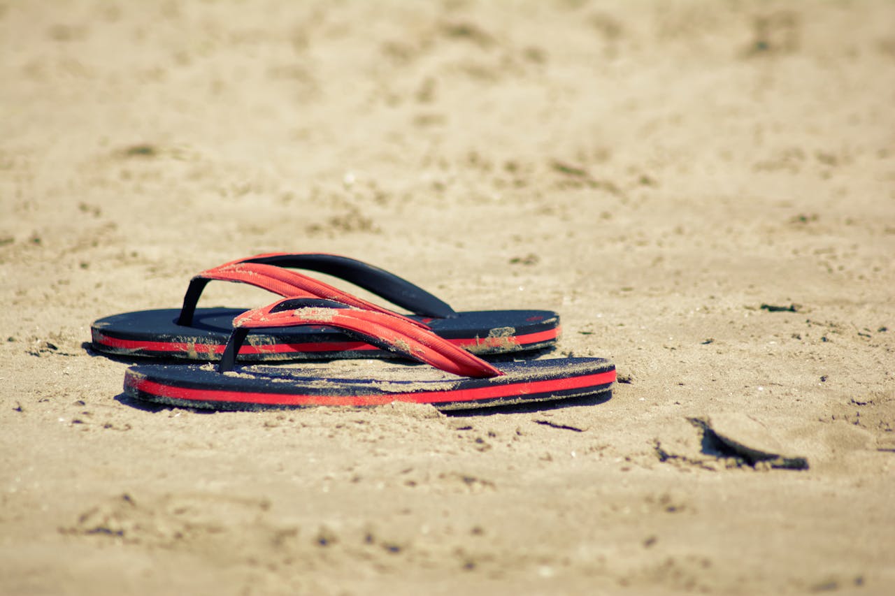 Red flip flops resting on a sandy beach capturing the essence of summer relaxation.